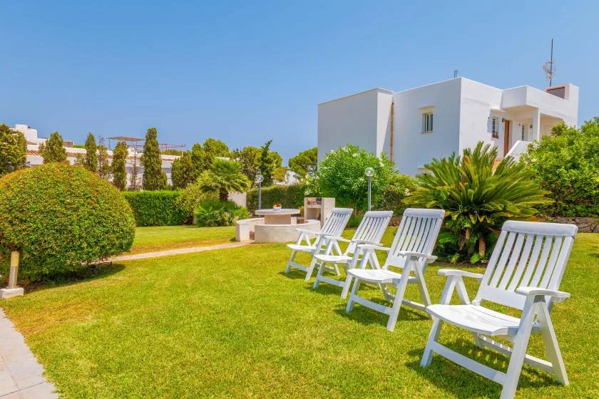 A sunny garden with lawn seating in front of a white building.