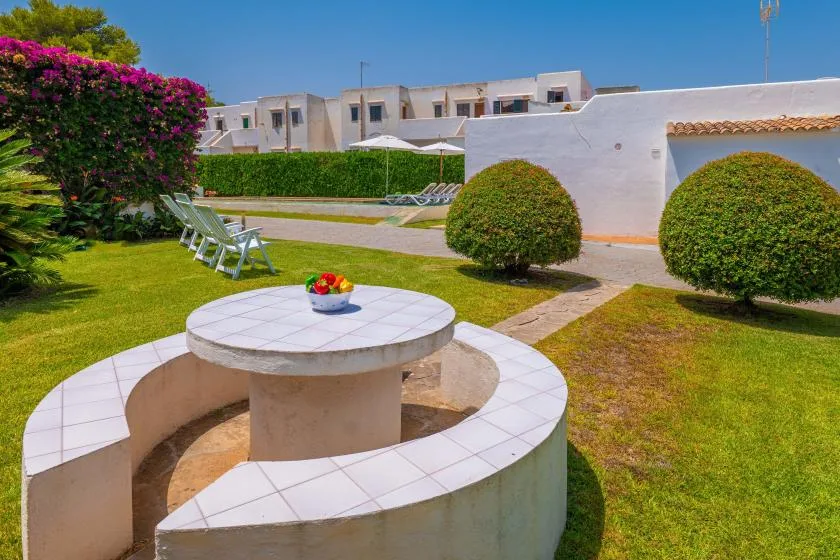 A landscaped outdoor courtyard with a round built-in seating area and trimmed shrubs.