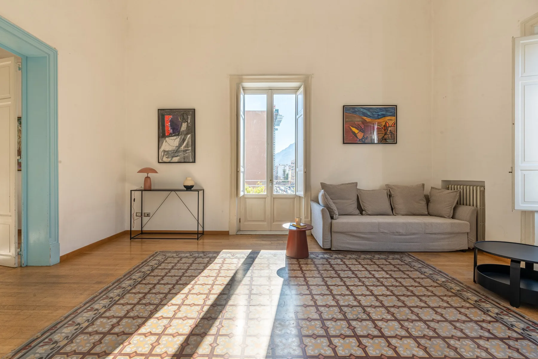 Una luminosa sala de estar con asientos, una alfombra estampada y ventanas altas.