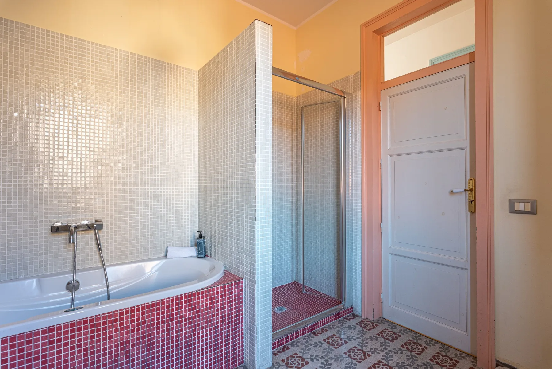 Un baño con azulejos, bañera, ducha y puerta.