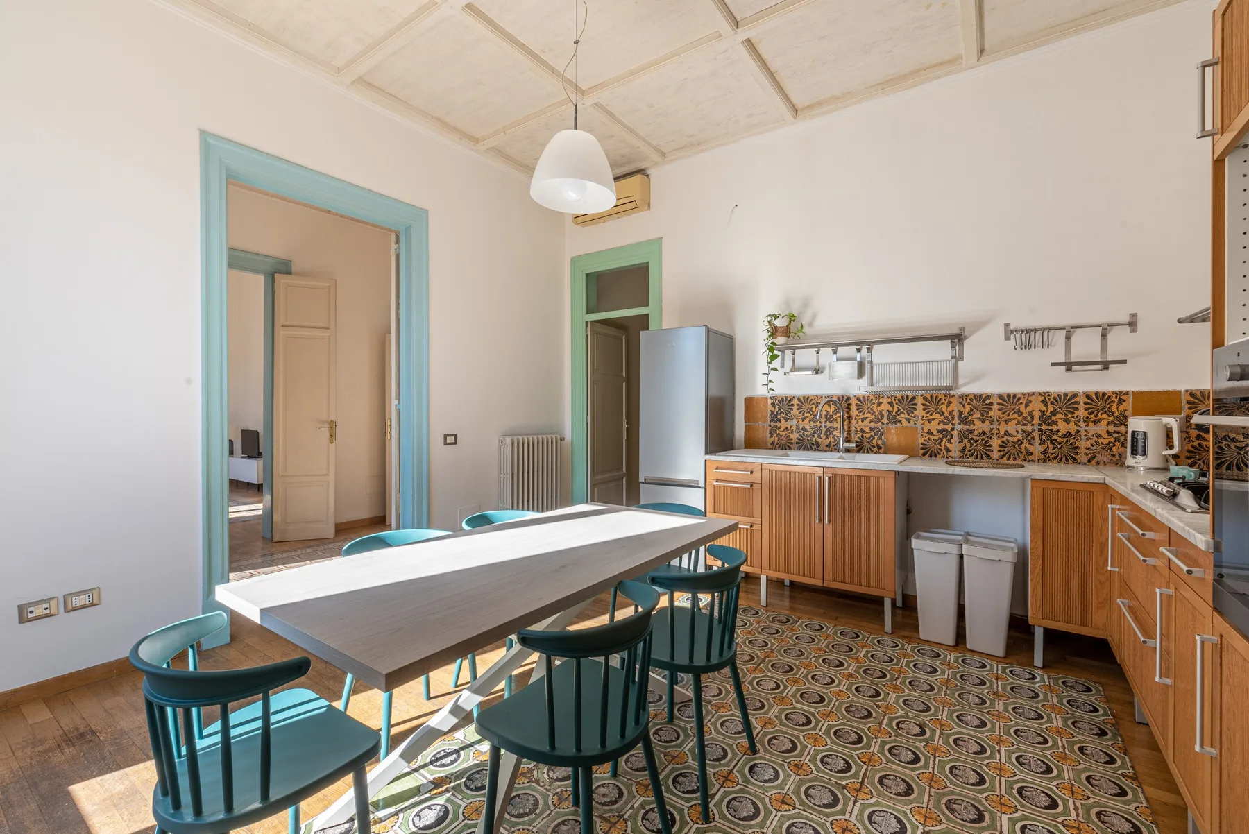Una cocina y comedor con una mesa larga, asientos y gabinetes de madera.