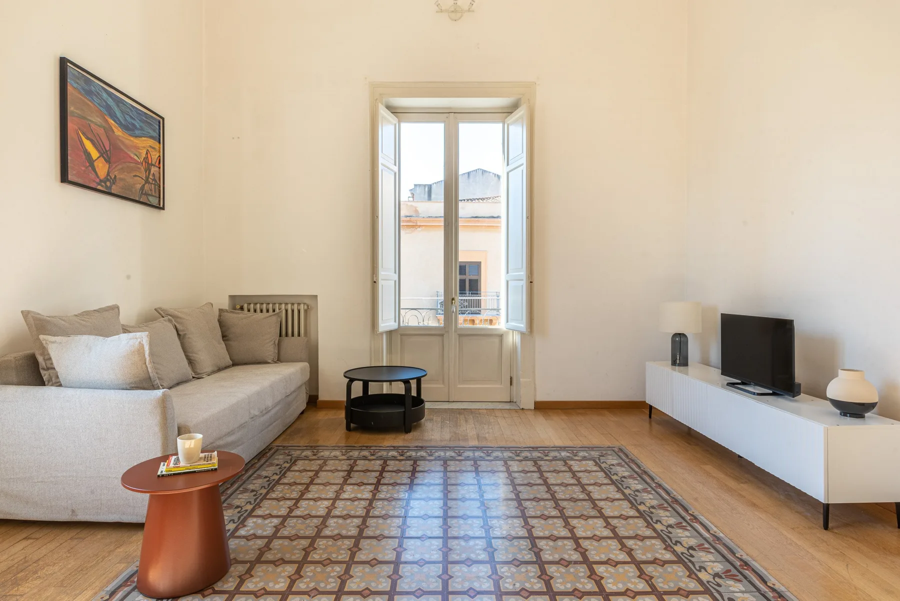 Una sala luminosa con asientos, una alfombra estampada y un televisor.