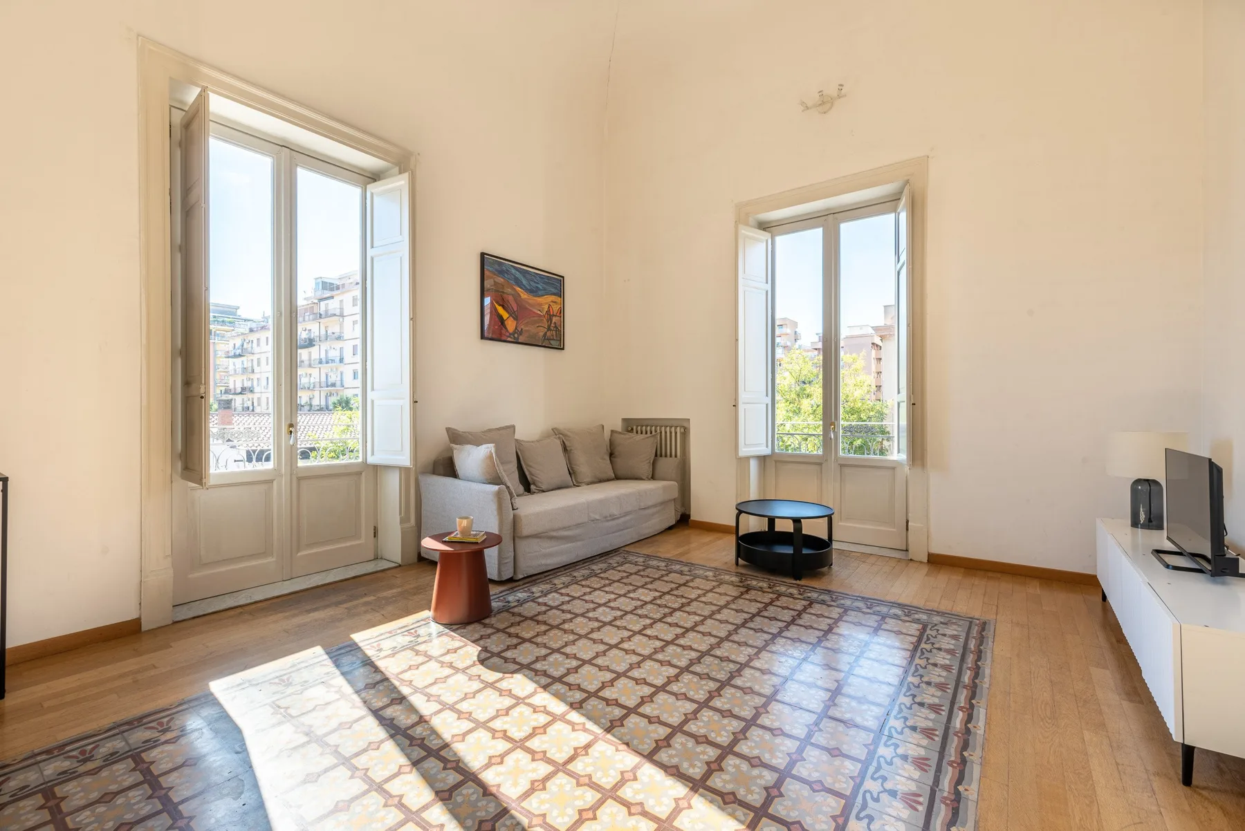 Una sala luminosa con asientos, ventanas altas y una alfombra estampada.
