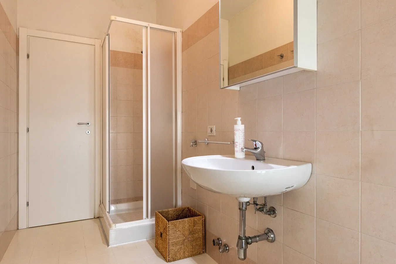 Un baño alicatado con ducha, lavabo y espejo de pared.