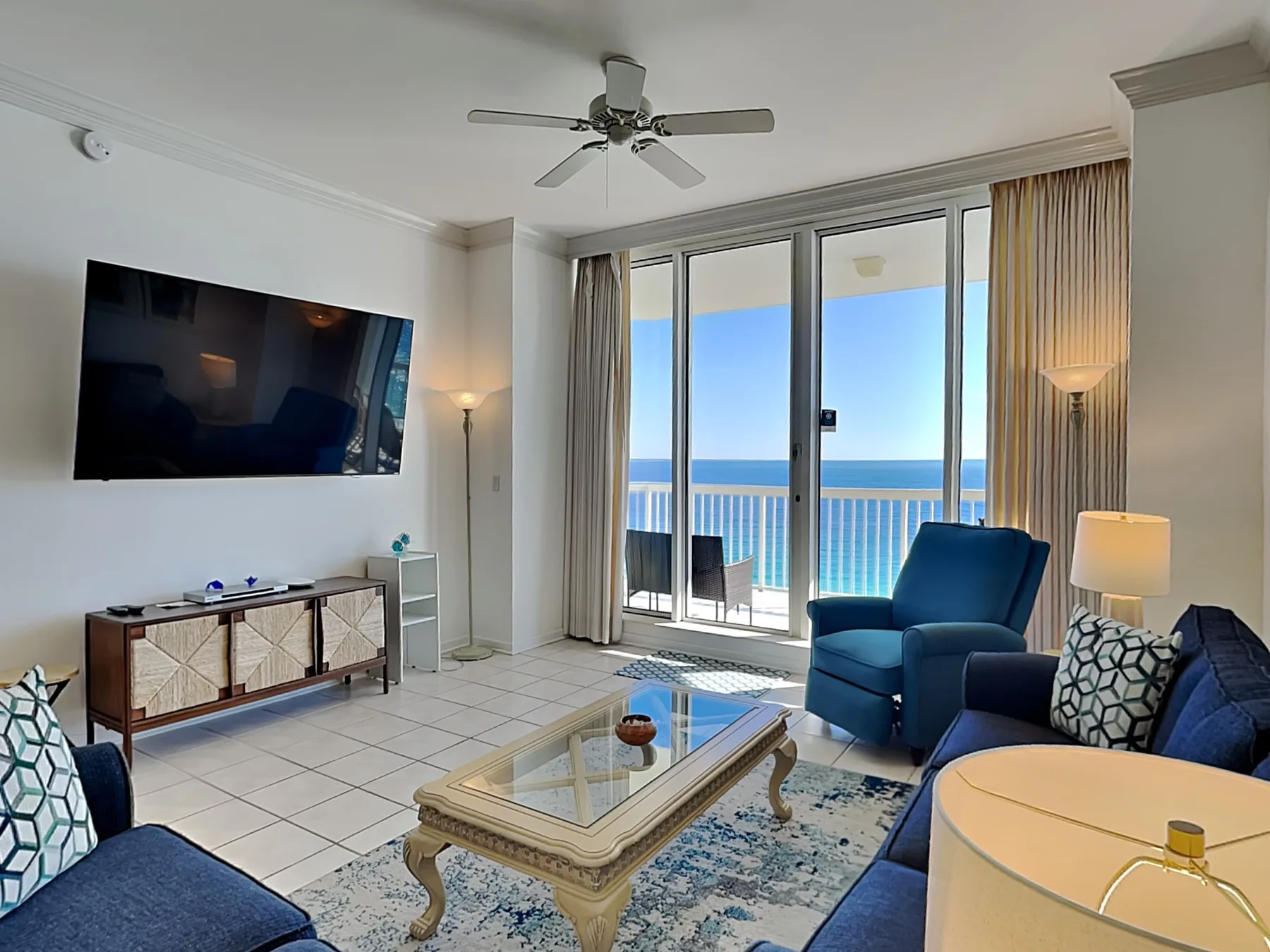 A living room with seating and a glass door opening onto a balcony.