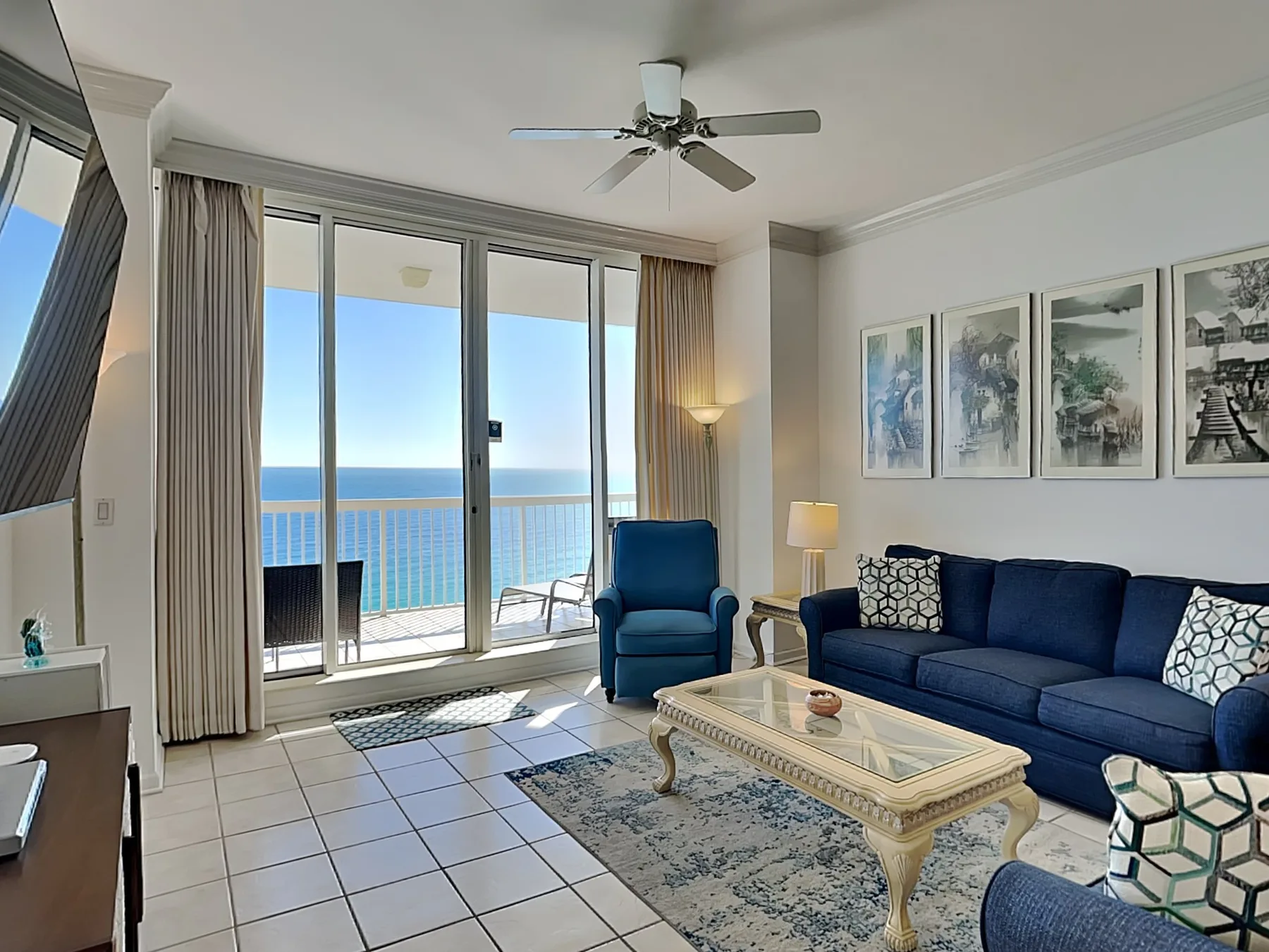 A bright living room with blue seating and glass doors opening onto a balcony.