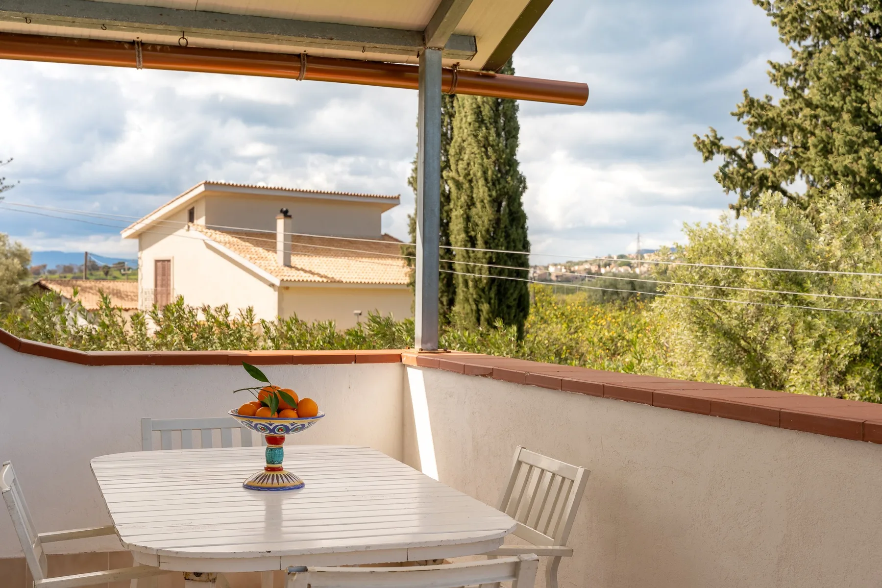 Una zona de comedor exterior cubierta con una mesa frente a árboles y edificios cercanos.
