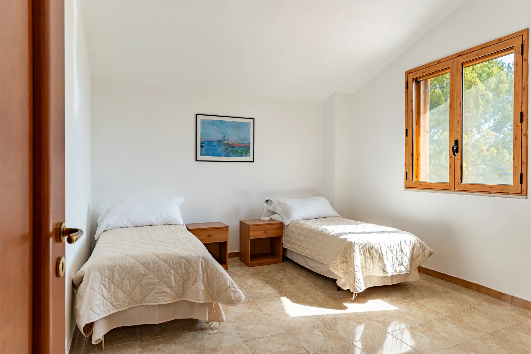 Un dormitorio luminoso con dos camas y una ventana soleada.