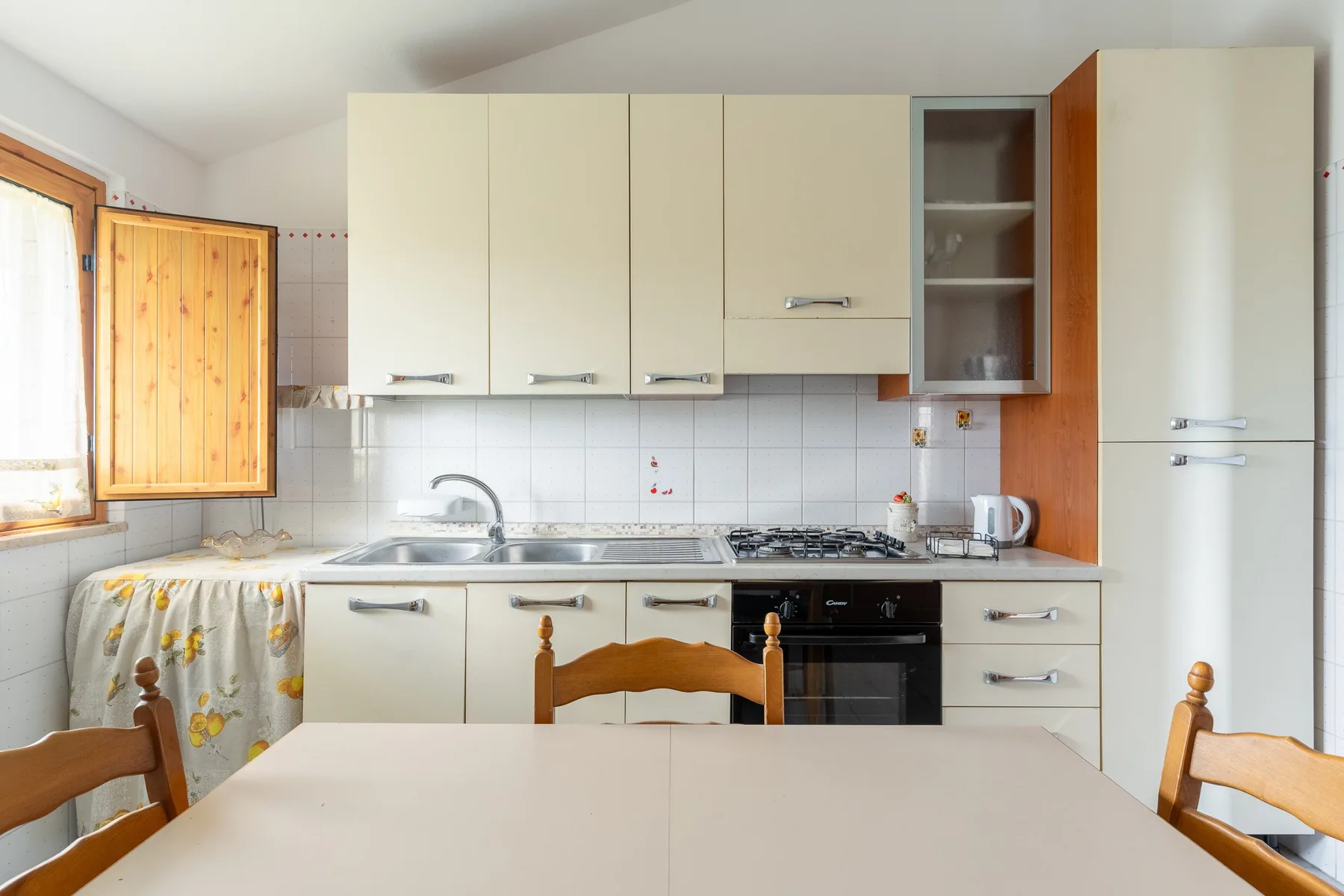 Una cocina luminosa con armarios claros, una encimera y una mesa de comedor.