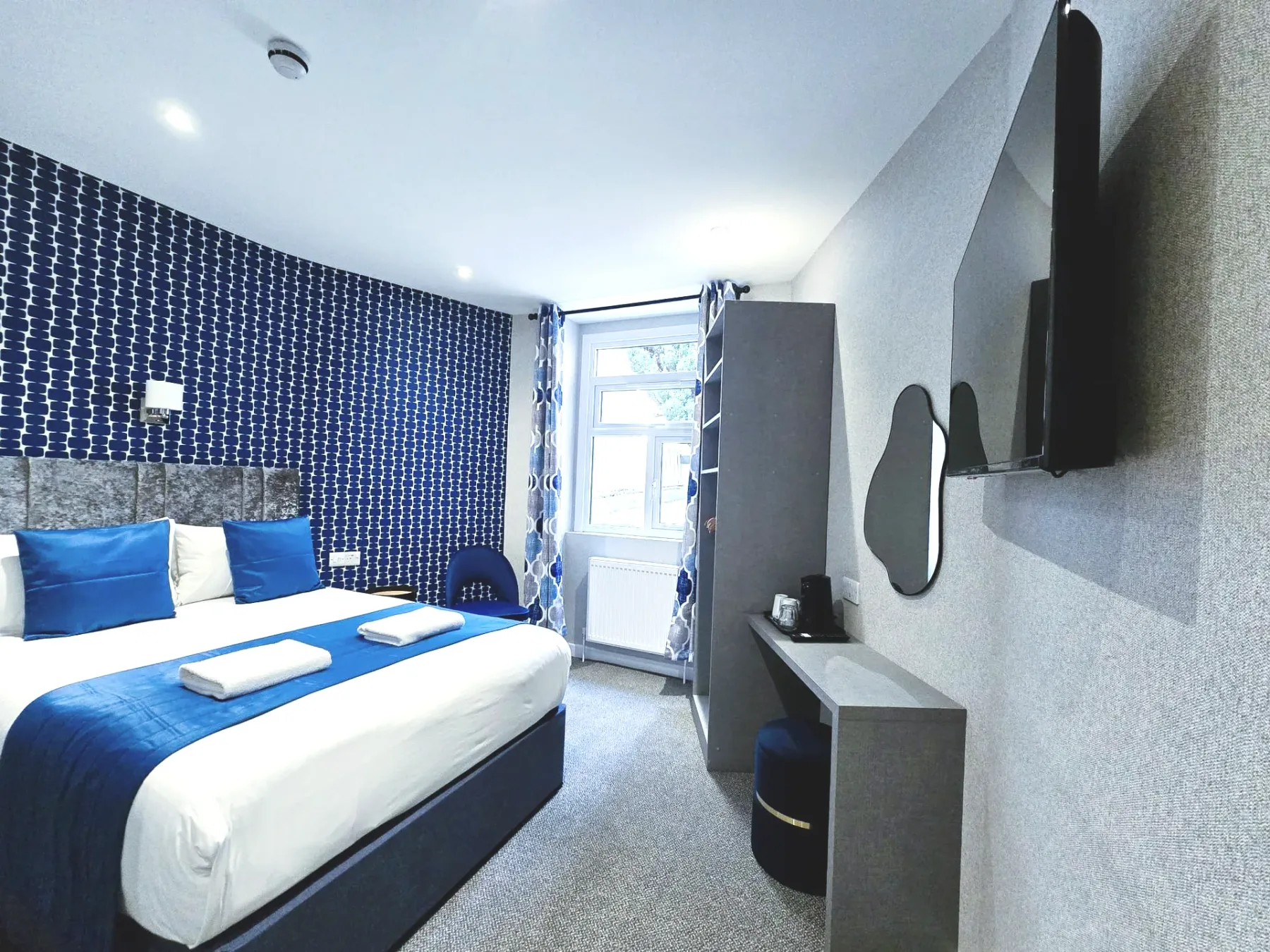 A hotel room with a king-size bed and a flat-screen television.