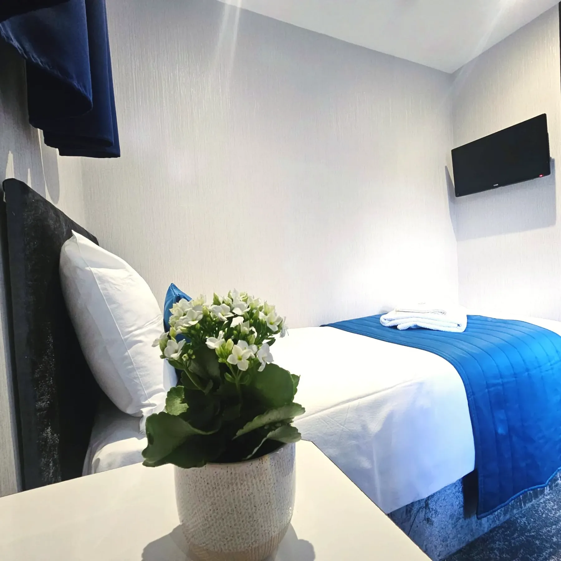 Un dormitorio con una cama y un jarrón con flores sobre una mesa.