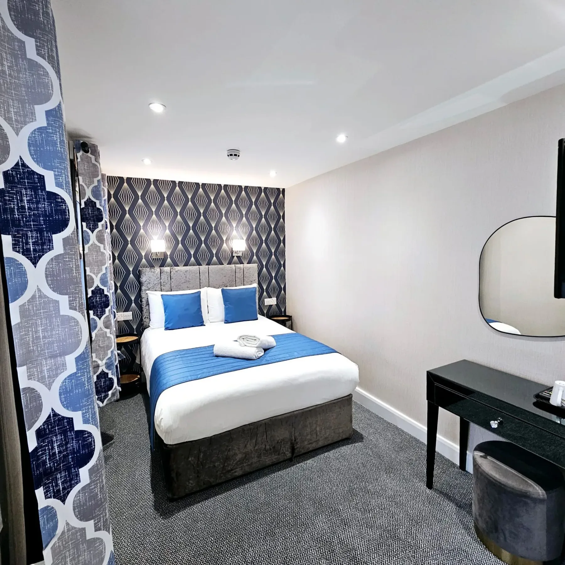 A hotel room with a large bed and a mirror.