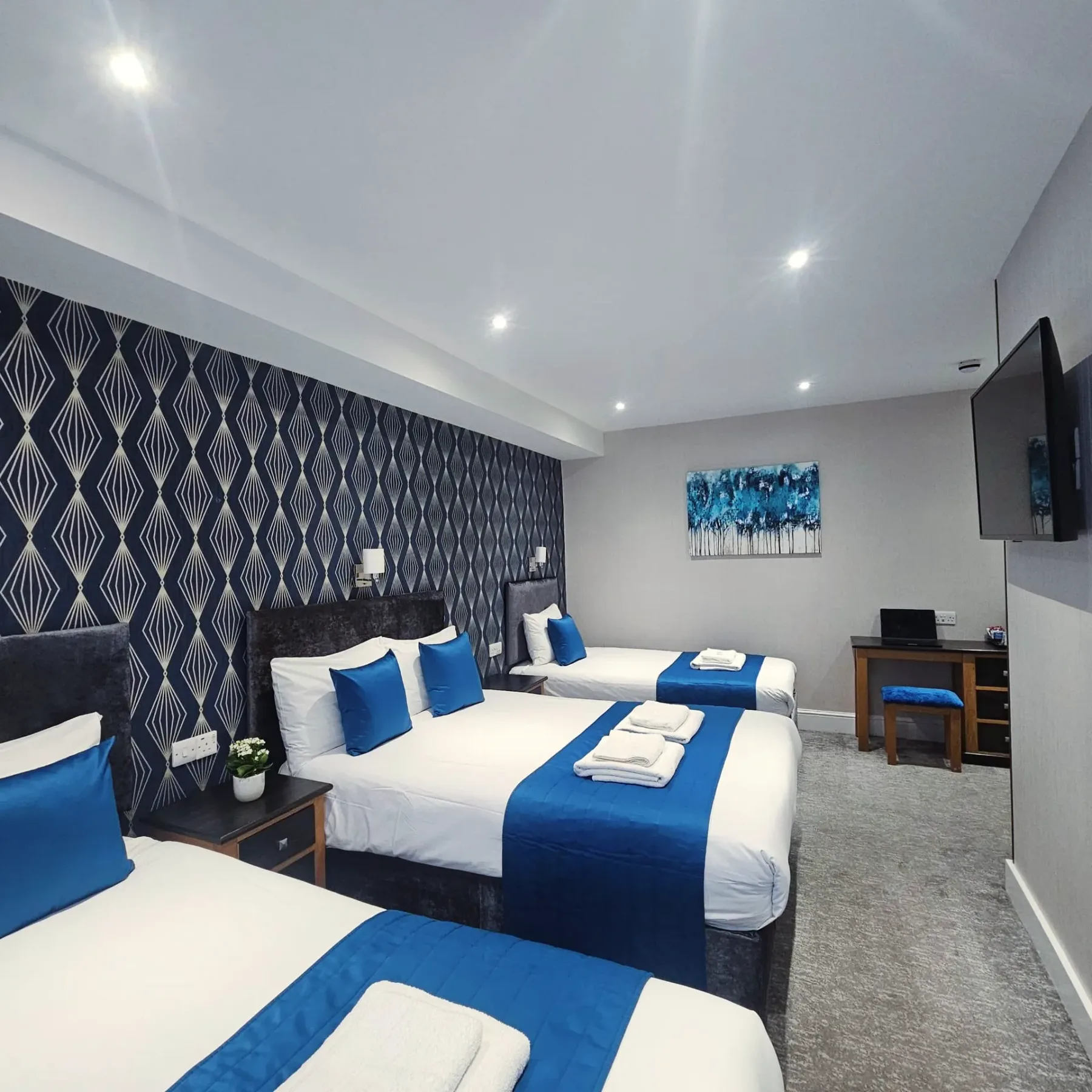 A hotel room with three beds and a flat-screen television.