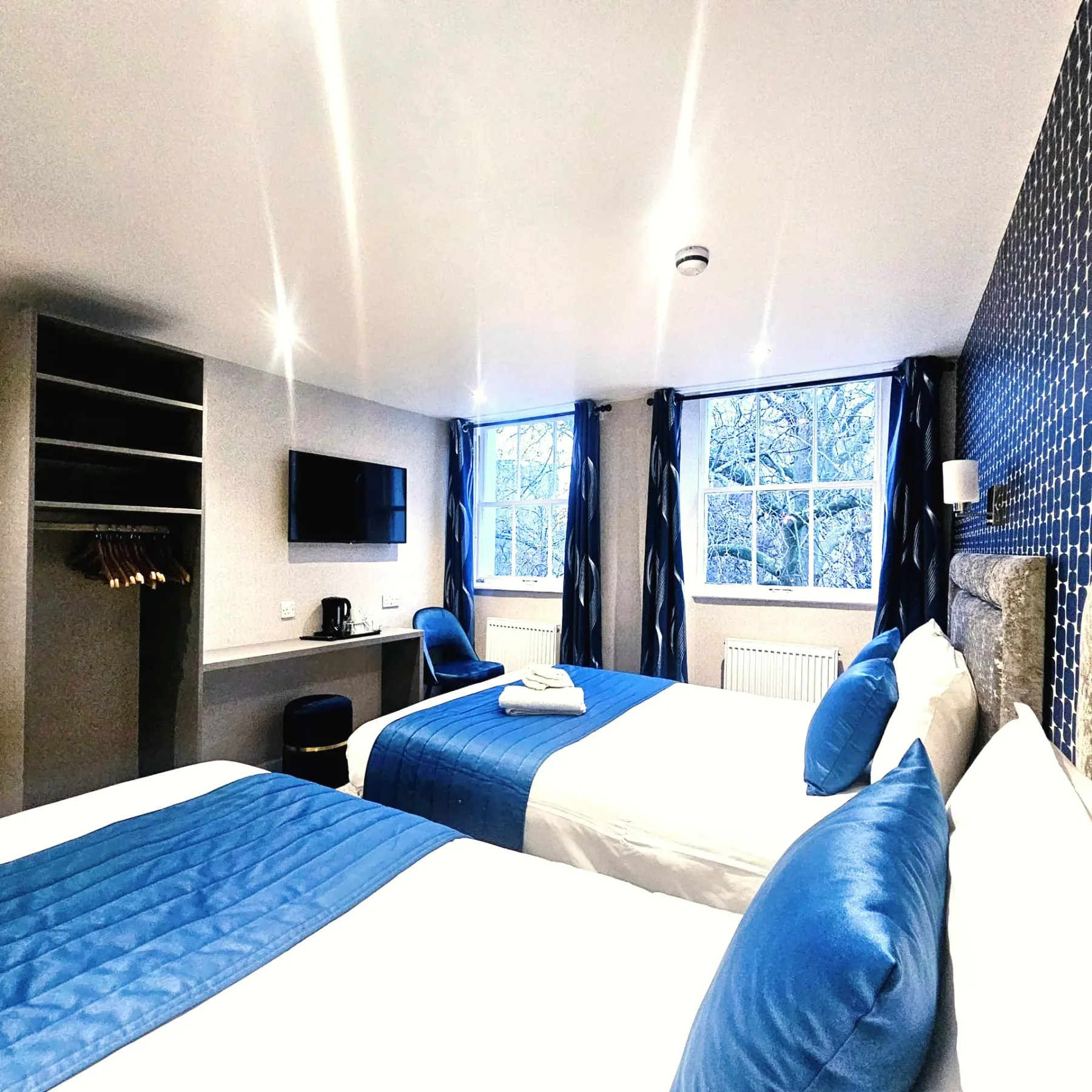 A hotel room with two beds and blue curtains.