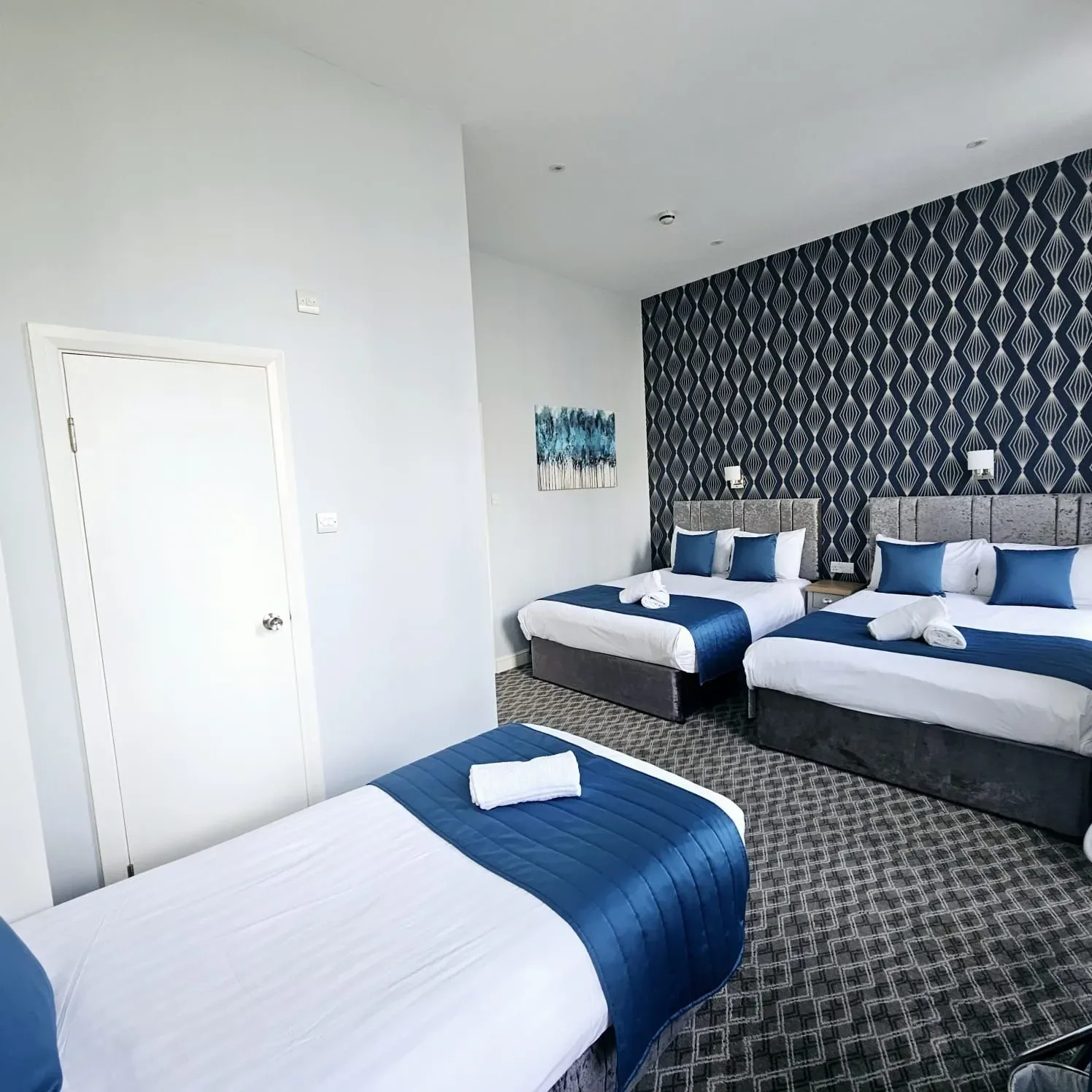A hotel room with two beds and a door.