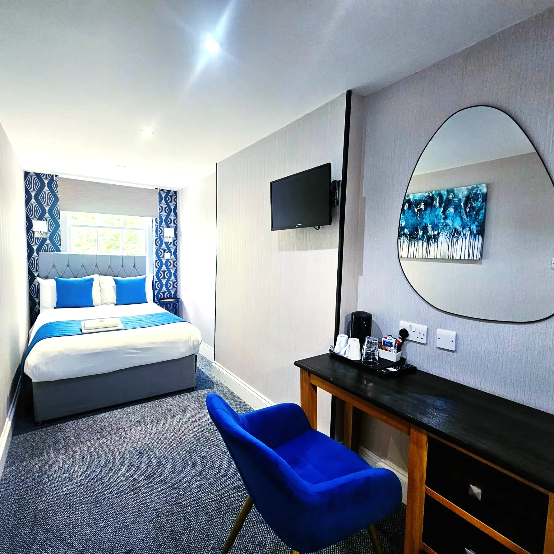 A hotel room with a bed, desk, chair and television.