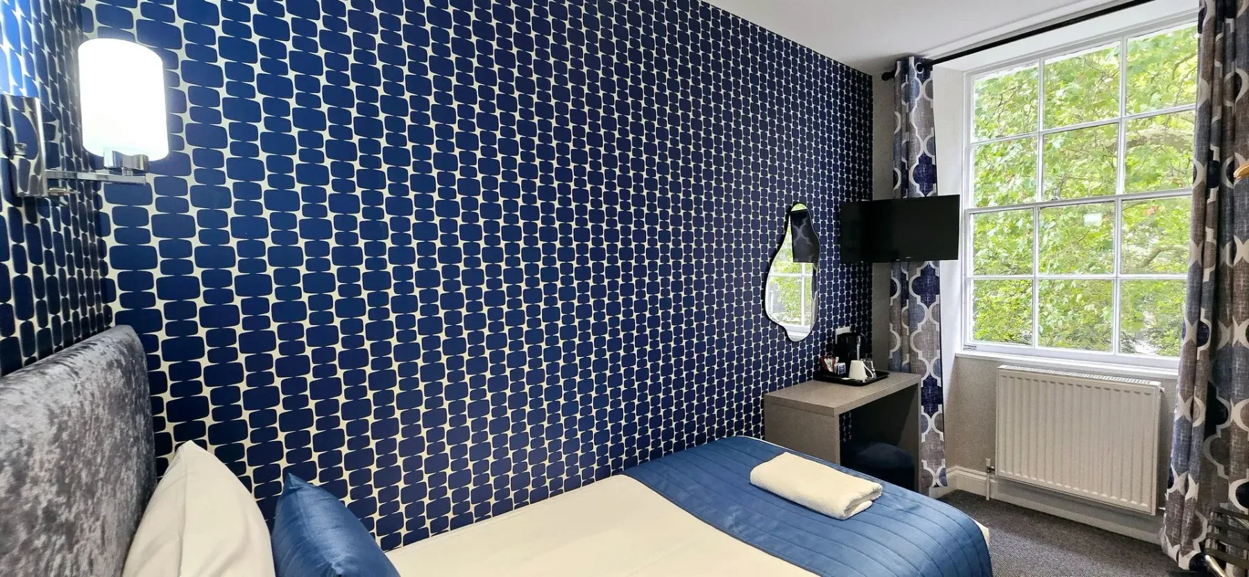 Una habitación de hotel con una cama, un escritorio y un televisor.