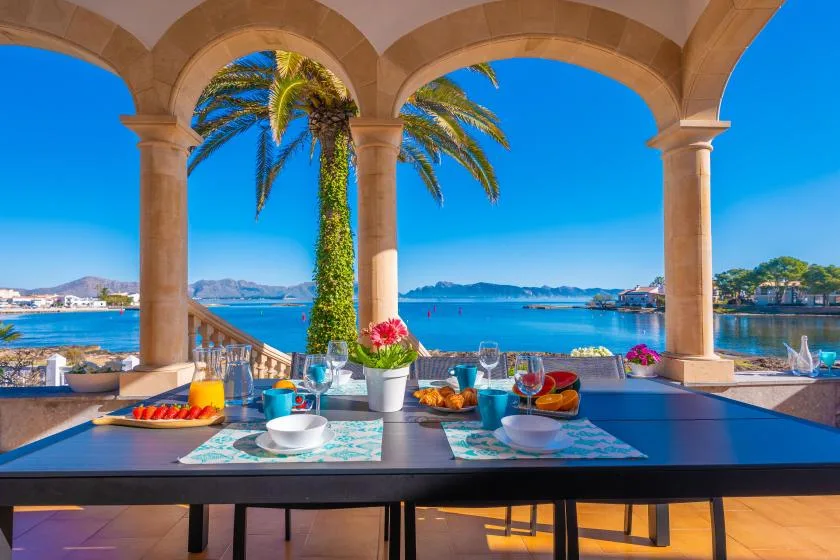 Una mesa puesta en una terraza abierta tiene vistas al mar.