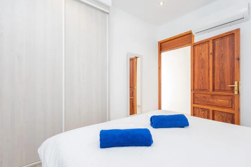 Dormitorio con una cama blanca, toallas azules y una puerta de madera.