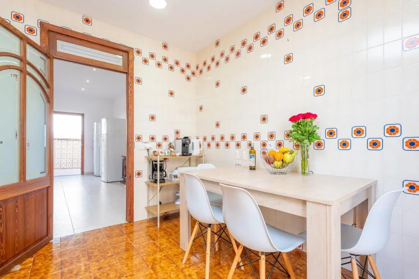 Una cocina y comedor alicatados con una mesa, sillas y electrodomésticos sobre la encimera.
