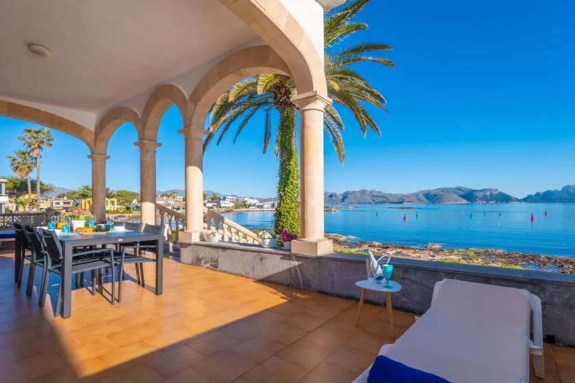 Una terraza frente al mar con arcos, asientos al aire libre y vistas al agua.