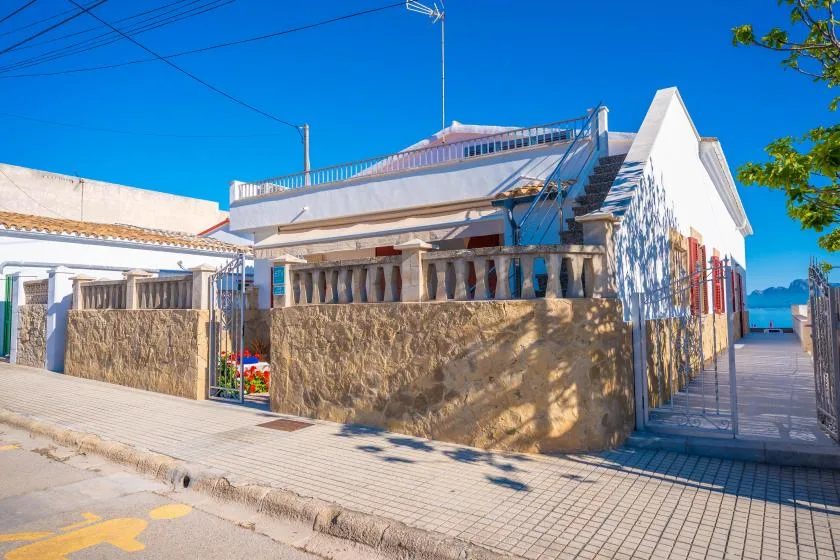 Un edificio blanco junto al mar con un muro de piedra y una terraza exterior.