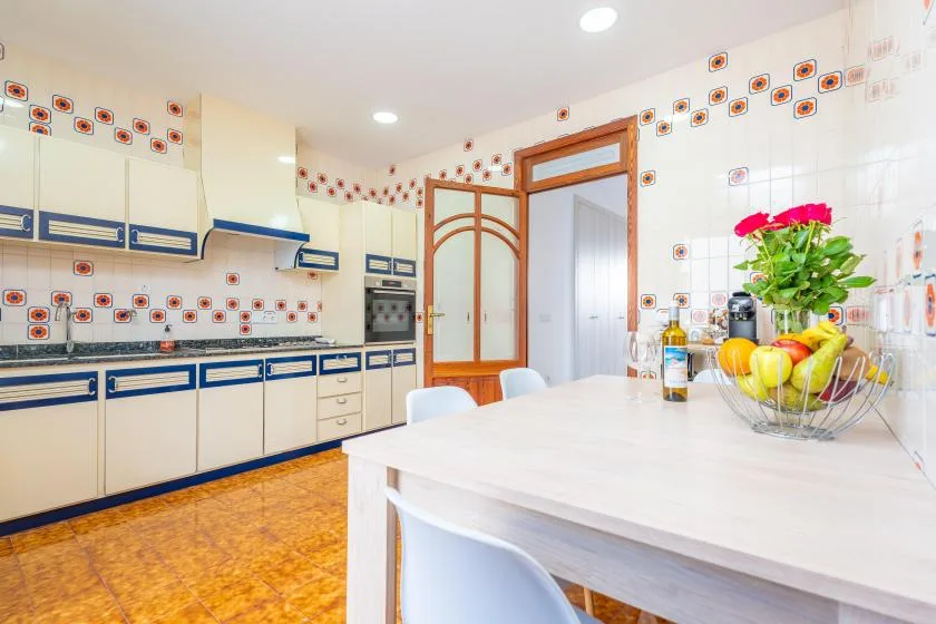 Una cocina luminosa con gabinetes azules y blancos y una isla blanca.