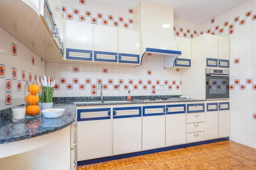 Una cocina luminosa con armarios de borde azul y un salpicadero de azulejos estampados.