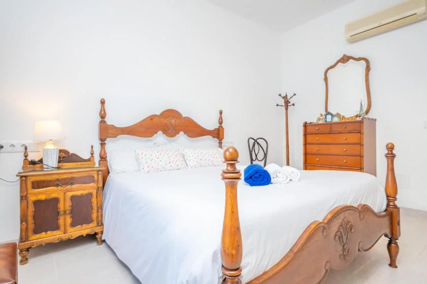 Un dormitorio con una cama de madera tallada, ropa de cama blanca y una cómoda.
