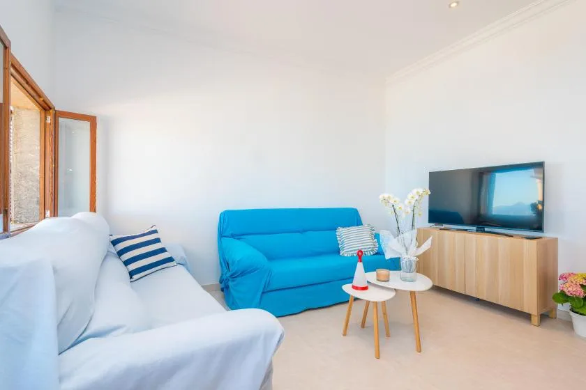 Una sala luminosa con asientos, un televisor y una pequeña mesa de centro.