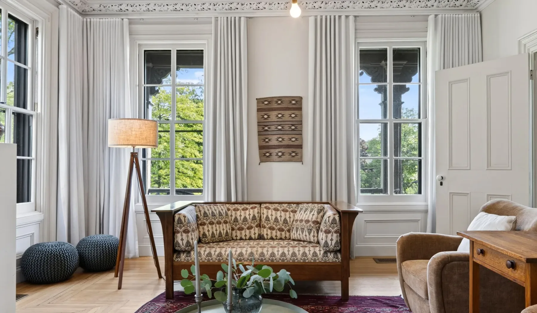 Una sala luminosa con asientos estampados y ventanas altas con cortinas.