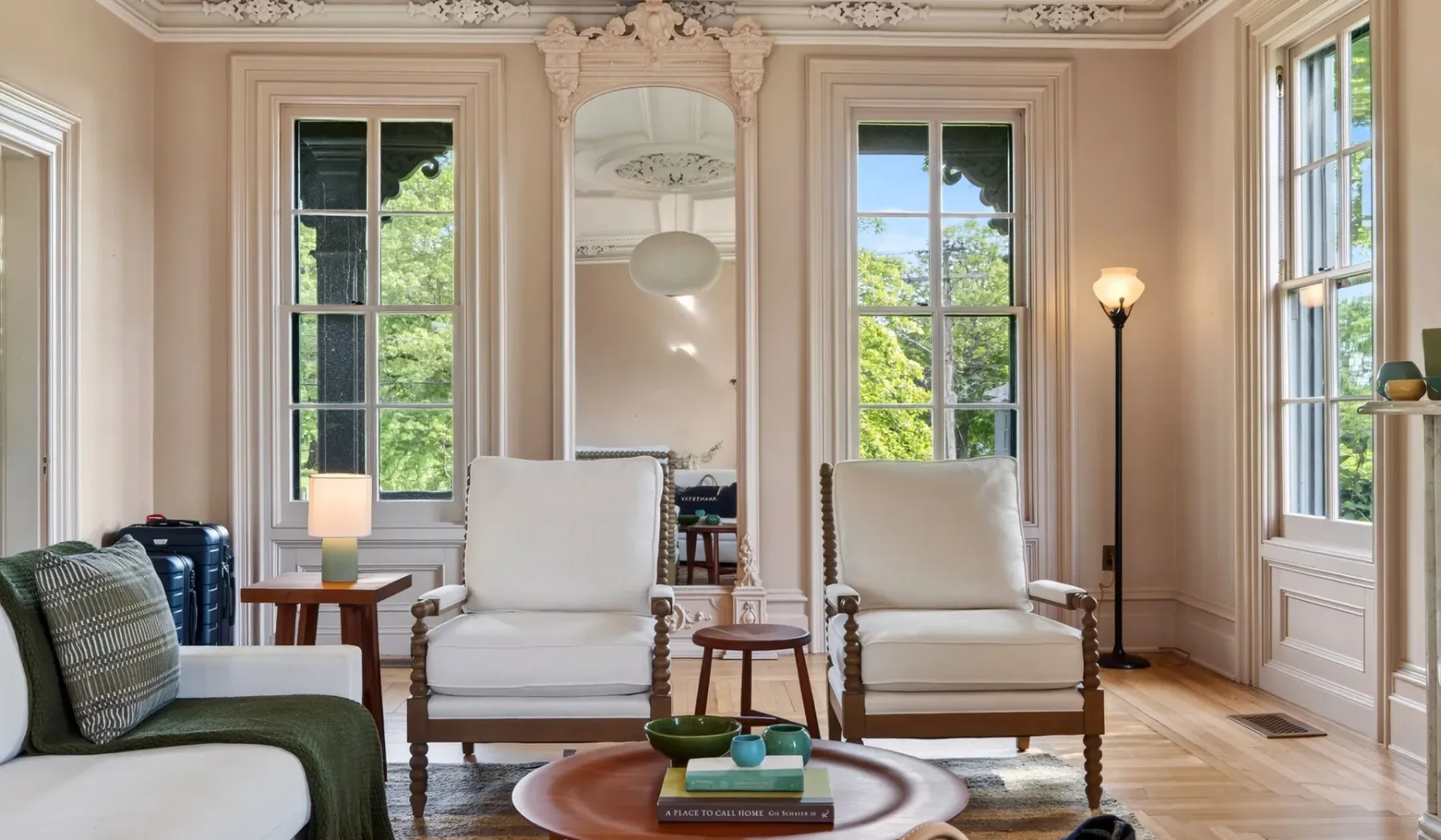 Una sala de estar luminosa con dos sillones junto a ventanas altas.