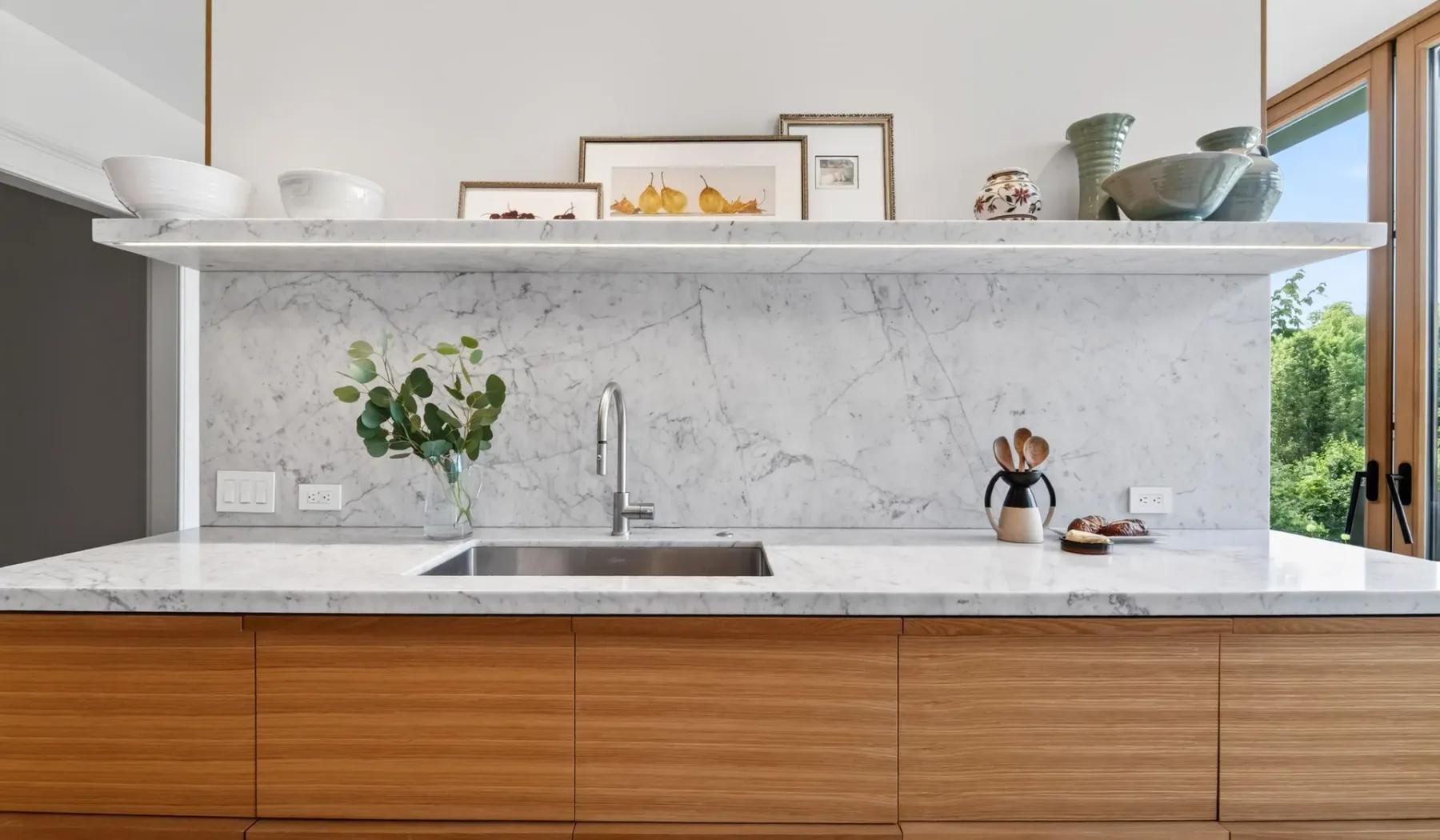 Una cocina moderna con salpicadero de mármol, fregadero y armarios de madera.