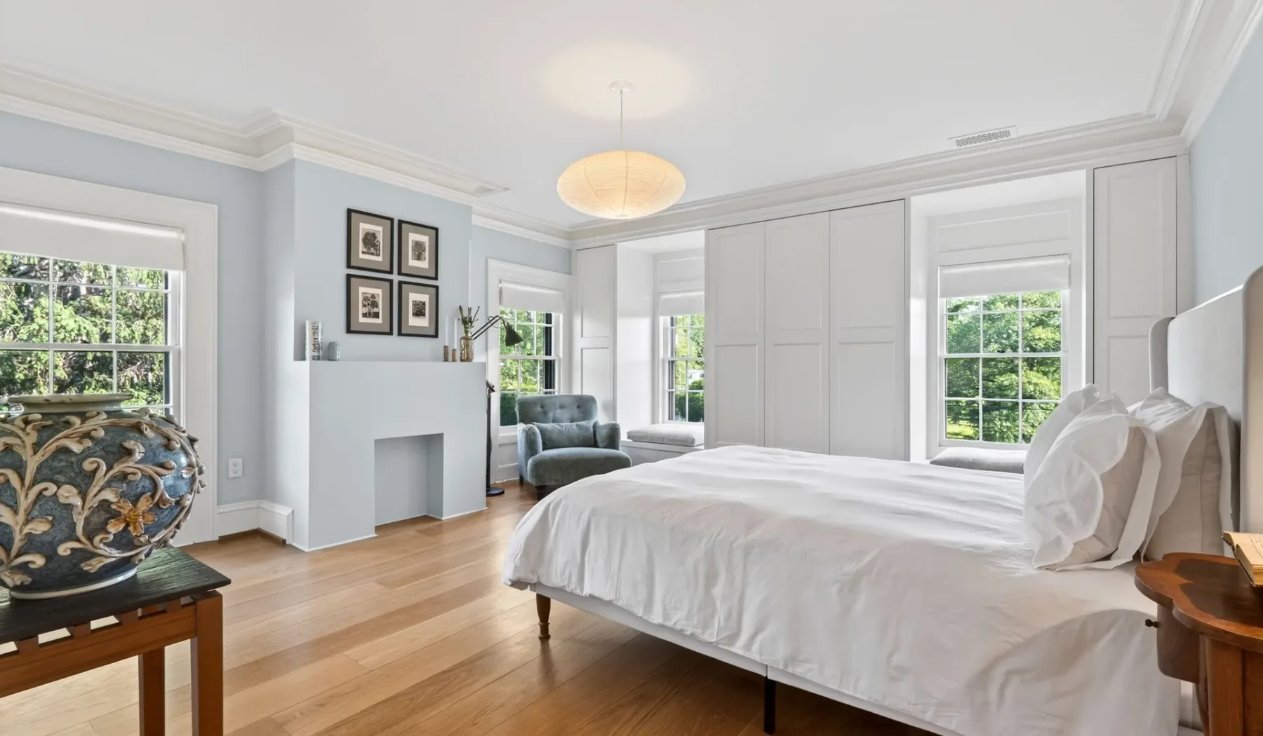 Un dormitorio luminoso con una cama grande, paredes claras y ventanas.