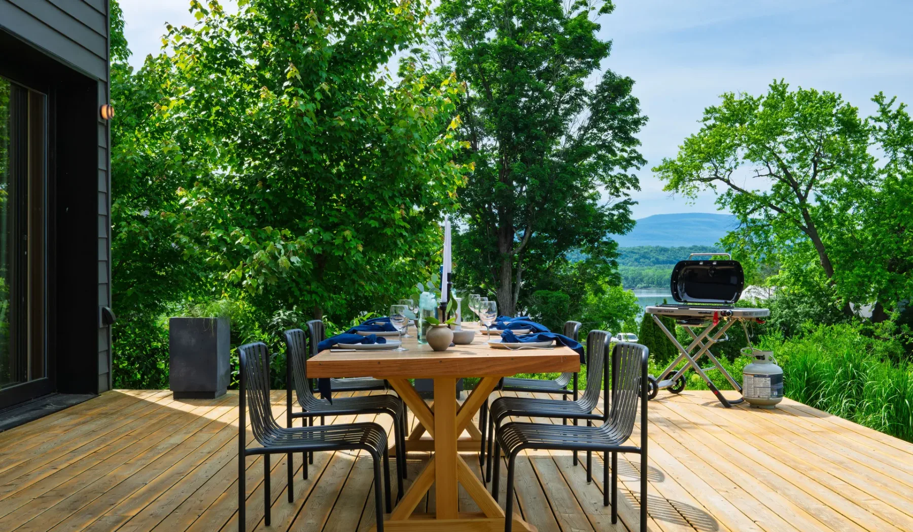 Un comedor al aire libre en una terraza de madera, rodeado de árboles.
