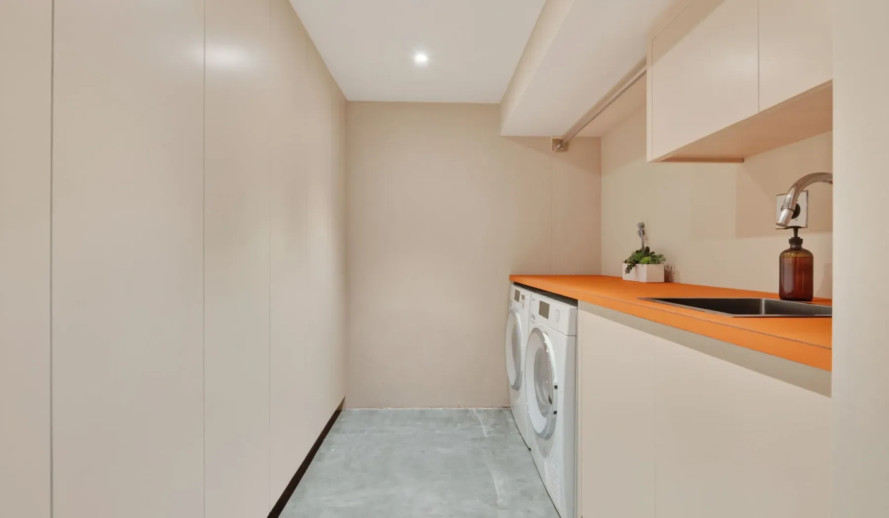 Un cuarto de lavado con una lavadora debajo de una encimera naranja.
