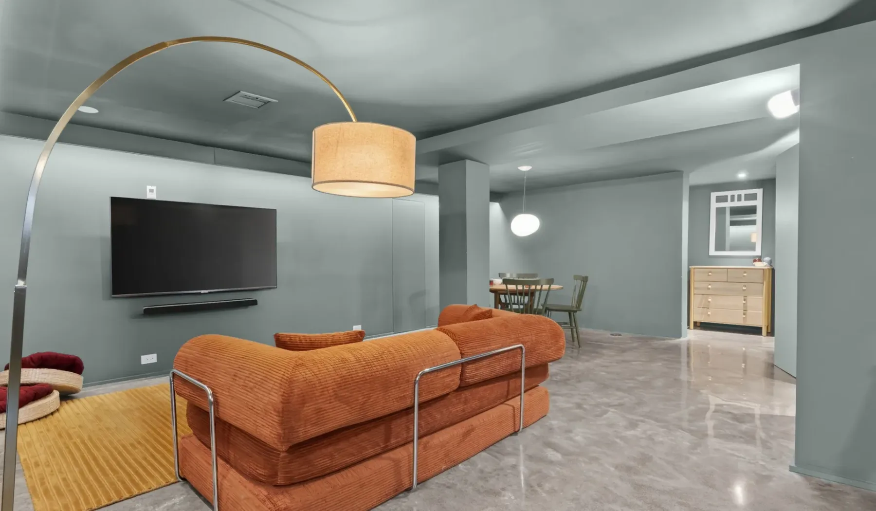 Una sala de estar con asientos naranjas, un televisor y un comedor.