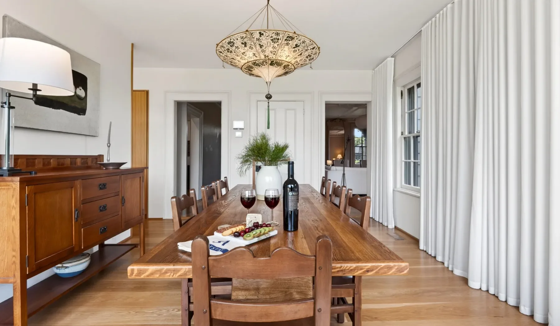 Comedor con una larga mesa de madera bajo una lámpara colgante.