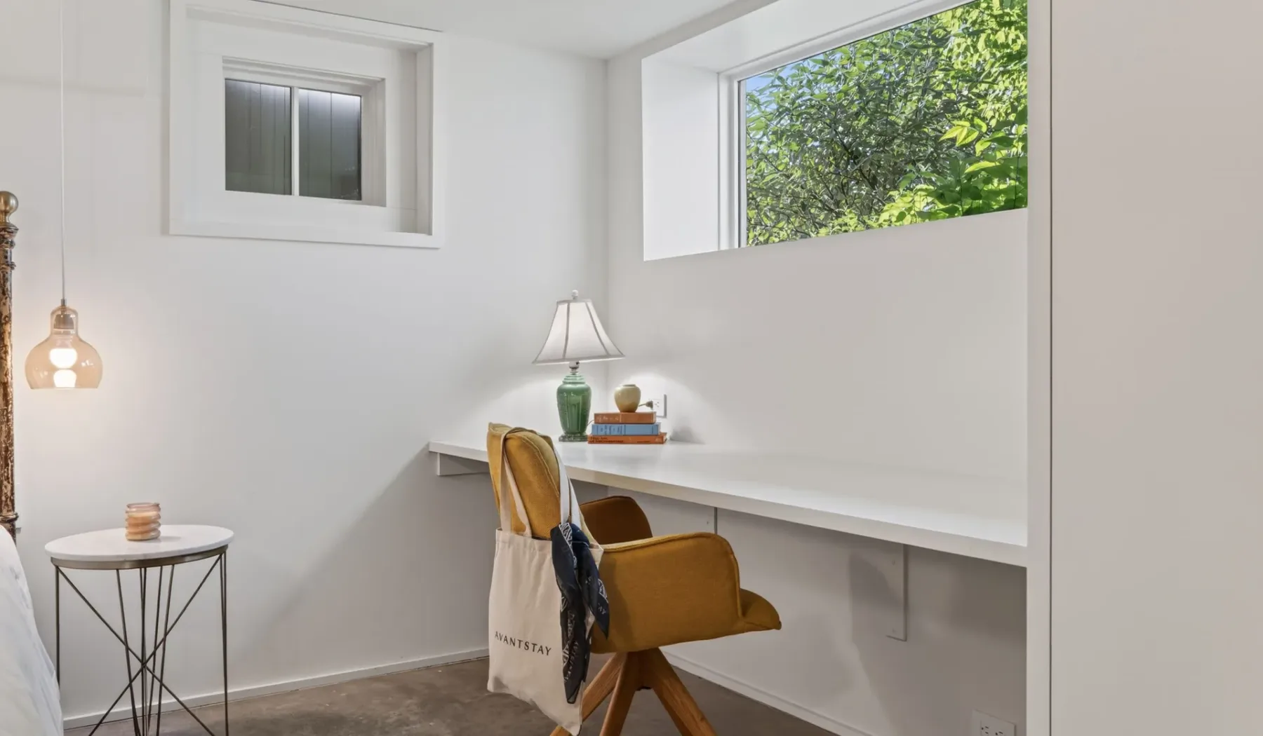 Un rincón de escritorio luminoso con una silla de madera y ventanas amplias con vistas a la vegetación.