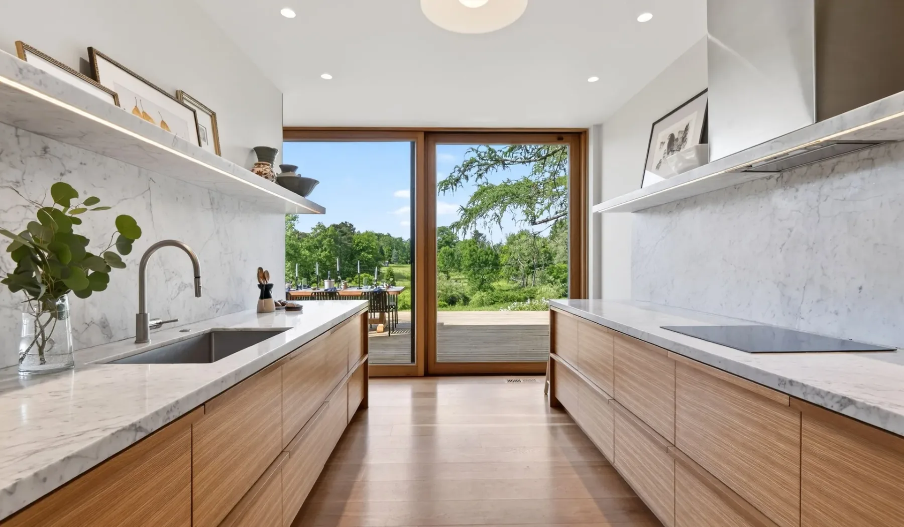 Una cocina luminosa con encimeras largas y grandes ventanas con vistas a la vegetación.