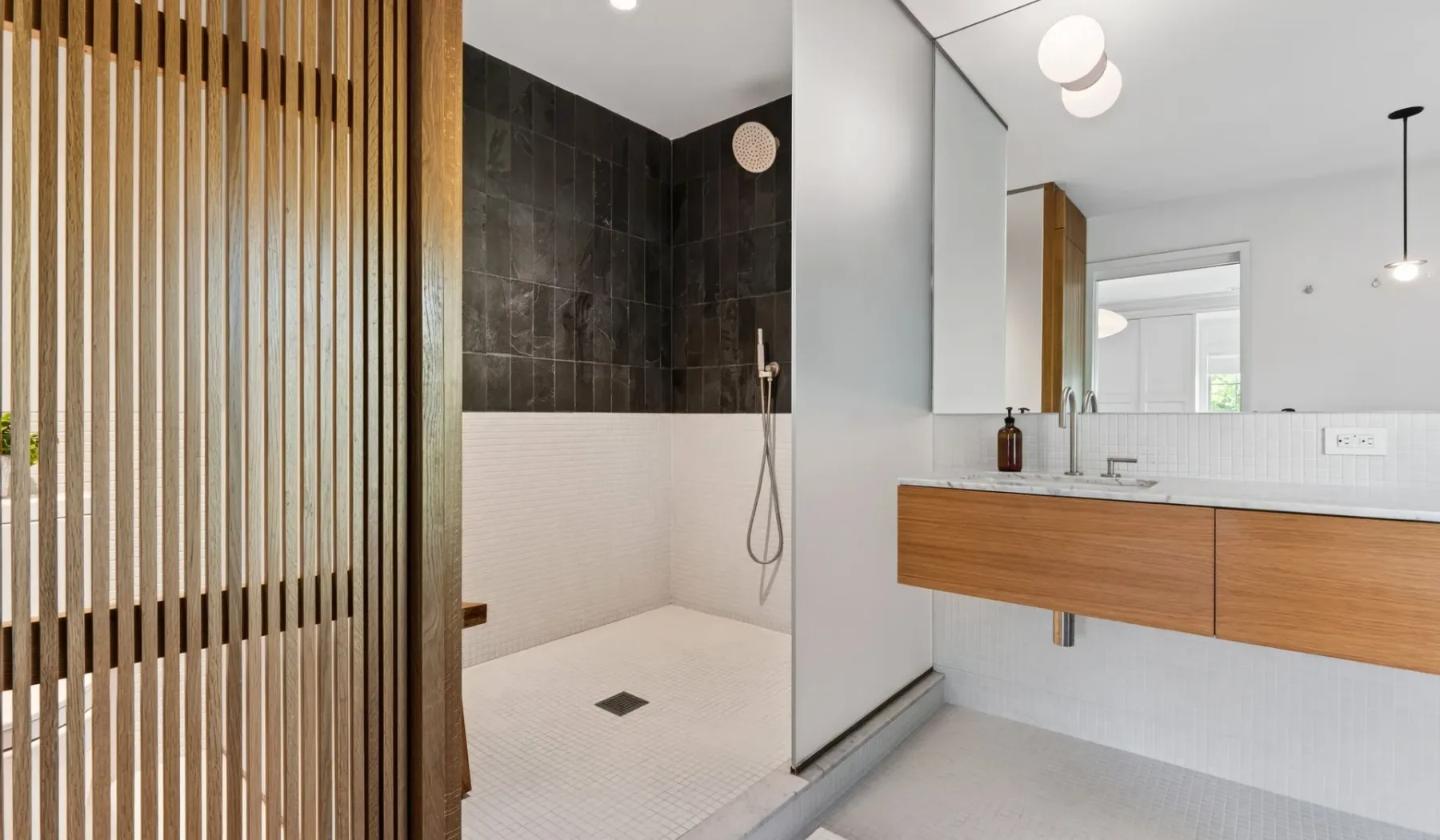 Un baño moderno con ducha abierta y un tocador flotante de madera.