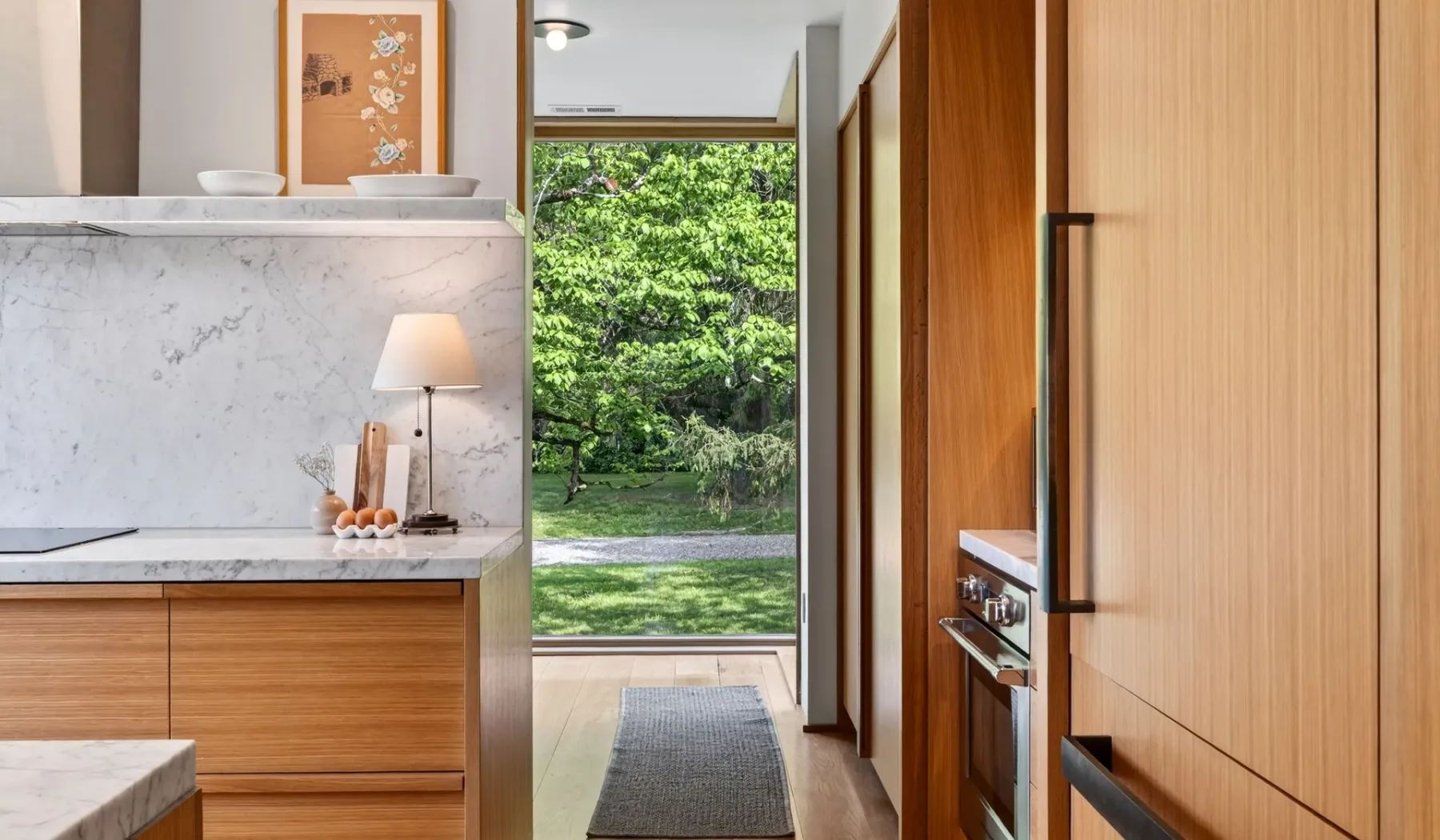 Una cocina se abre a través de una puerta hacia un jardín verde.