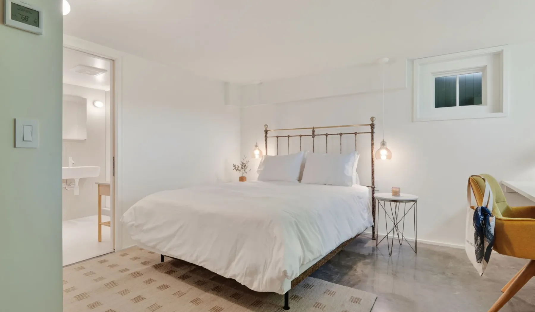 Un dormitorio luminoso con una cama bien hecha y luces colgantes junto a la cama.