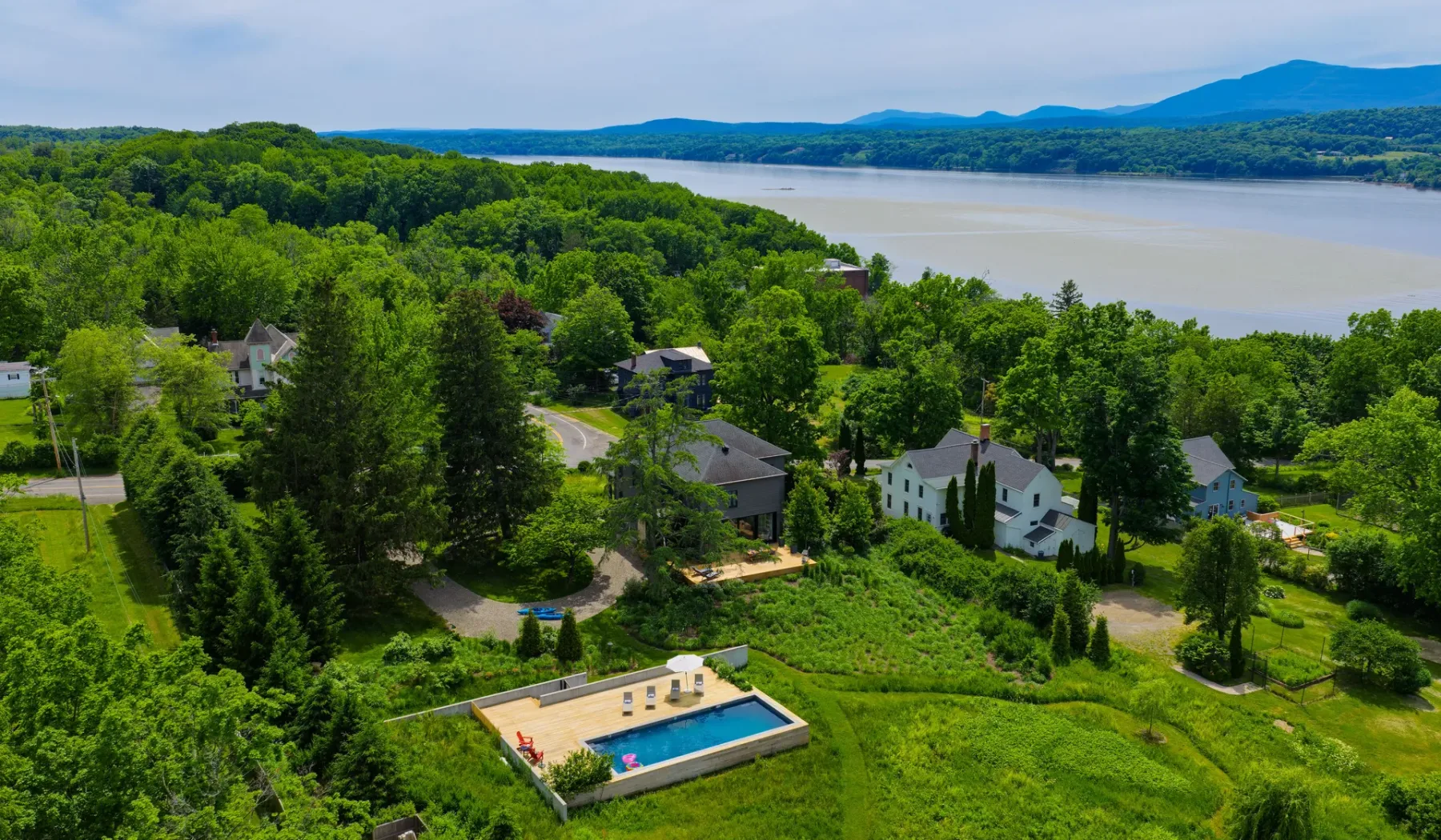 Vista aérea de una propiedad junto al lago, rodeada de vegetación y con piscina.