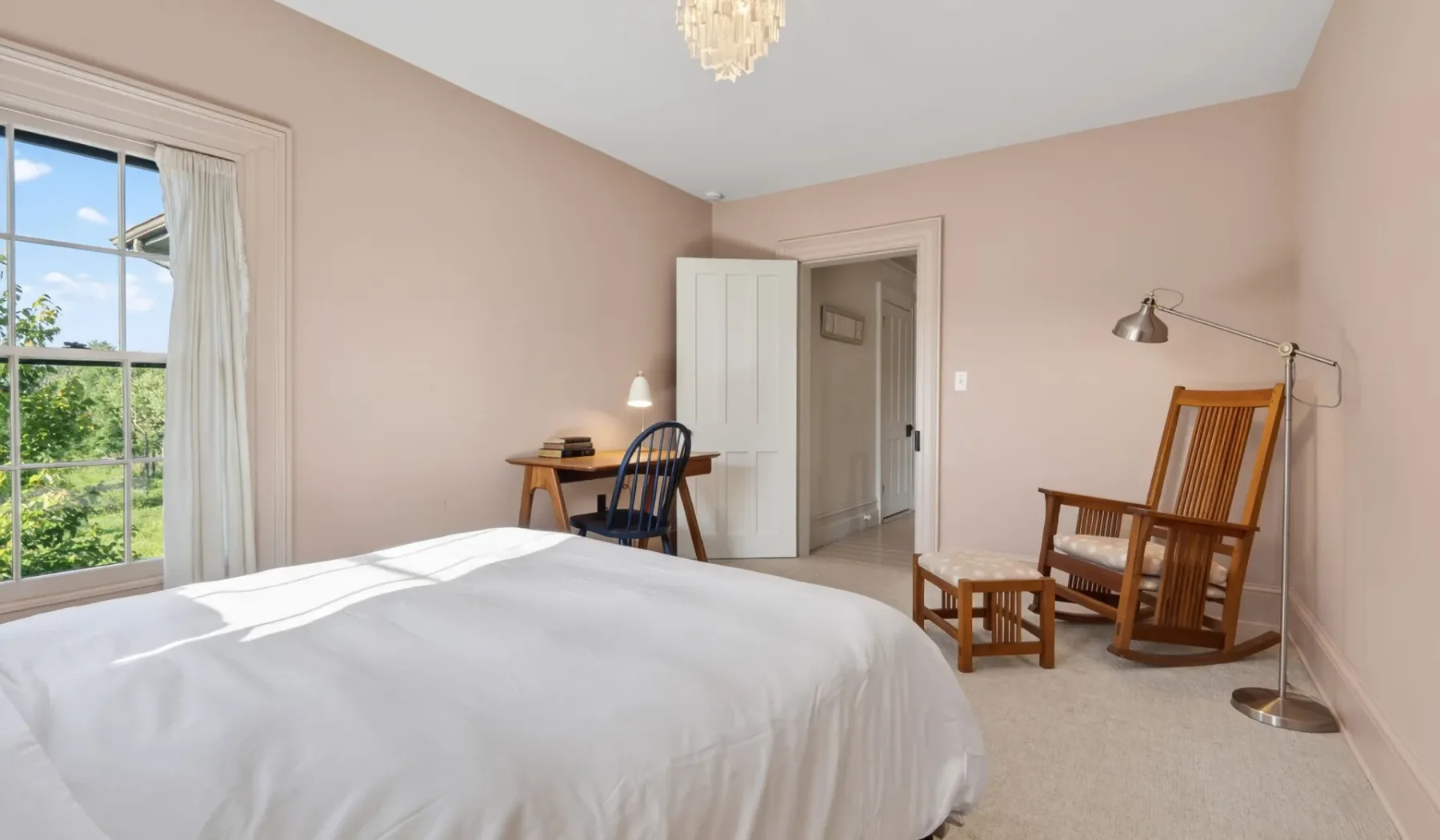 Dormitorio con una cama, un escritorio y asientos de madera junto a la ventana.