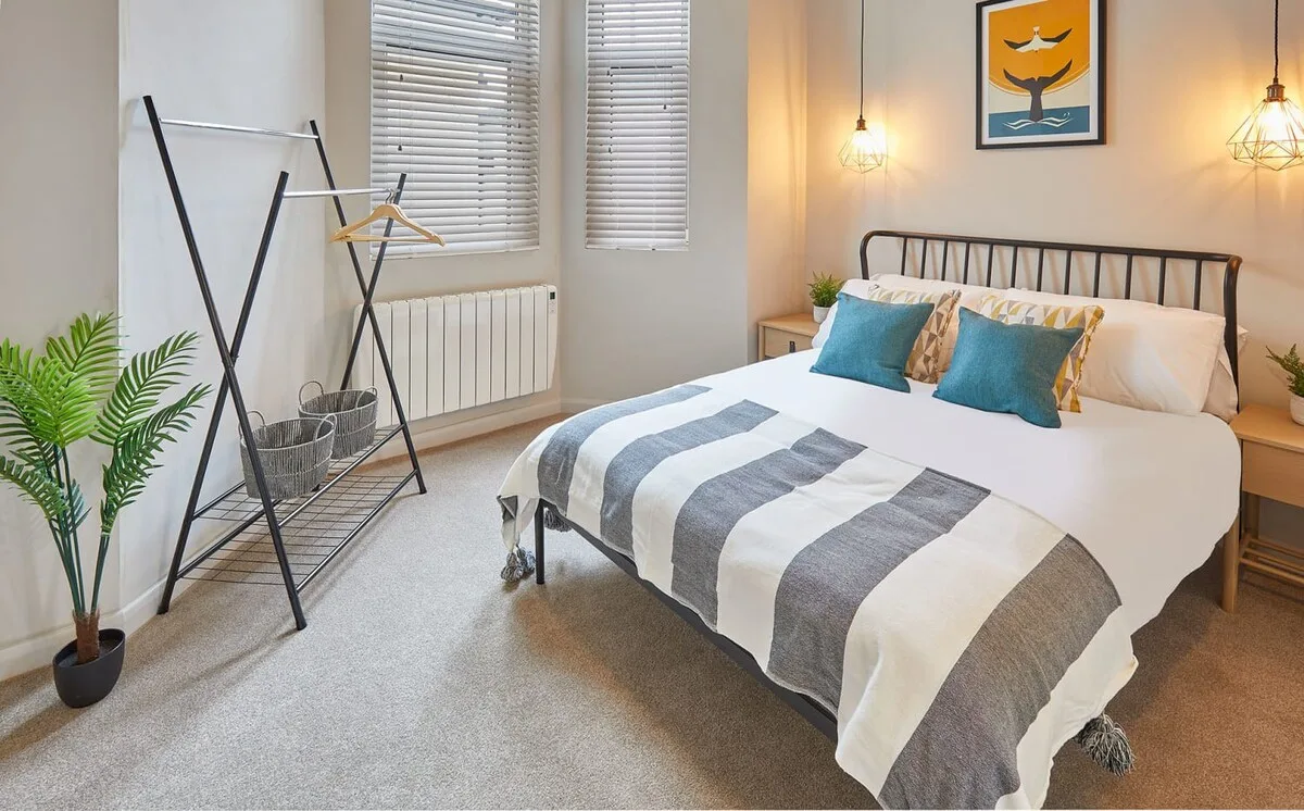 A bedroom with a neatly made bed and striped bedding.