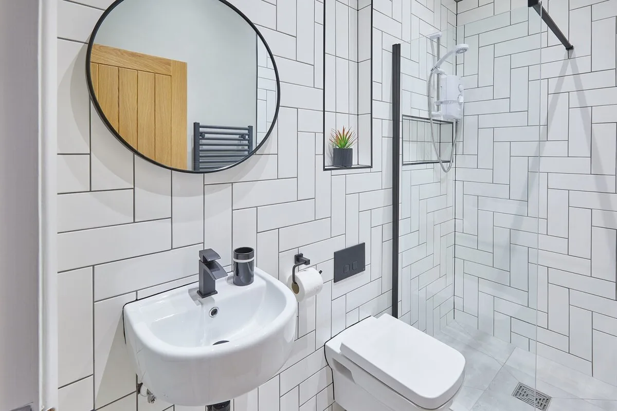 A tiled bathroom with a sink, toilet, and glass shower.