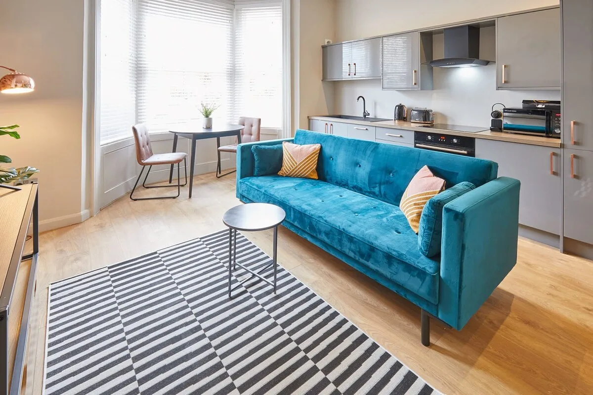 A living area with a blue sofa, coffee table, and open kitchen.
