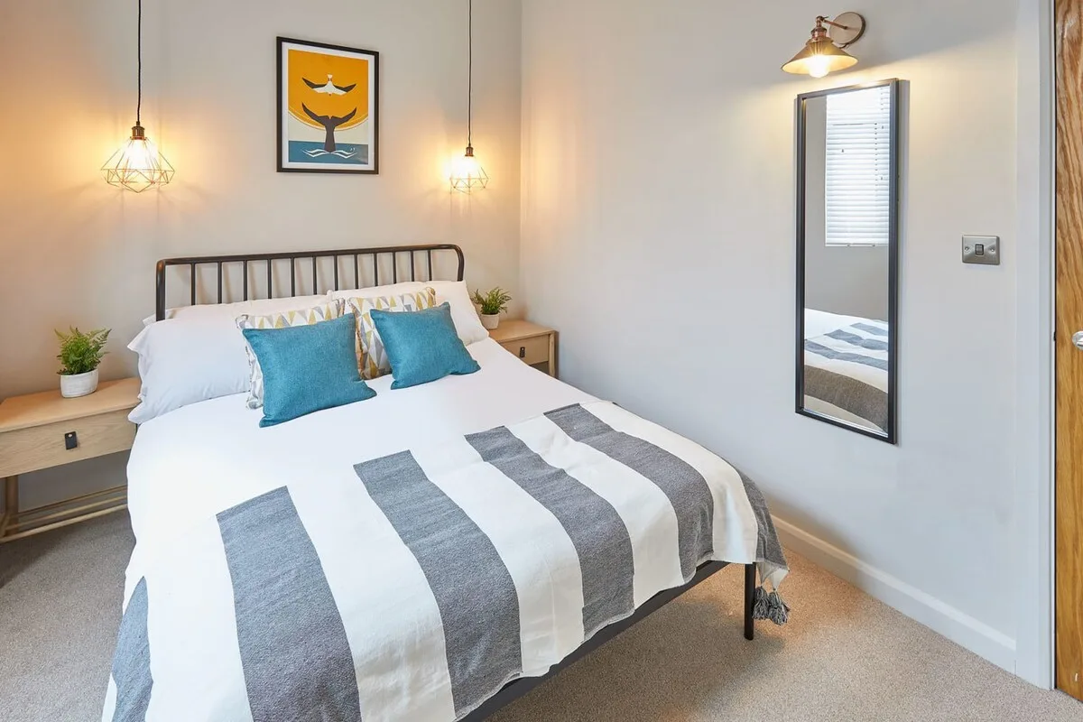 A bedroom with a neatly made bed and striped bedding.