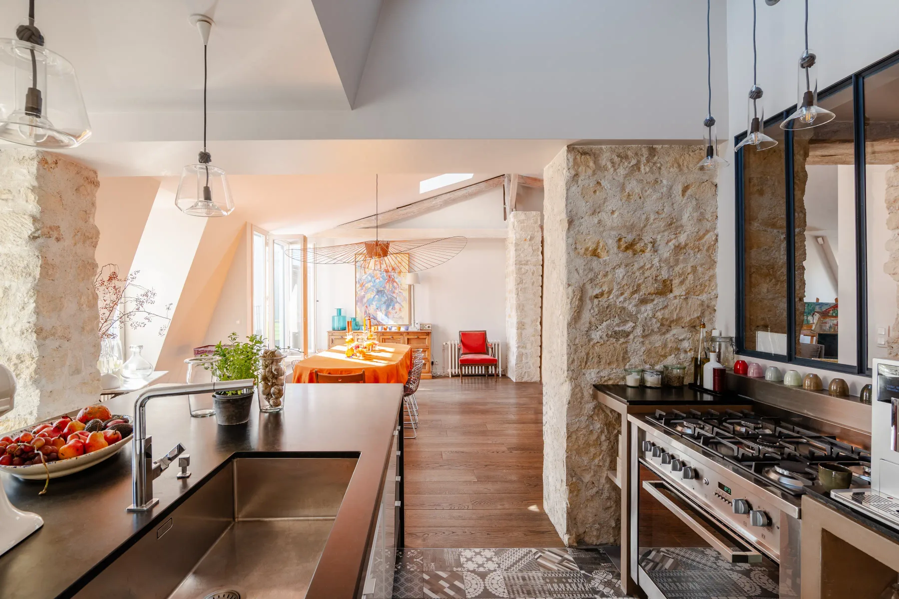 An open kitchen and dining area with a long table and stone walls.